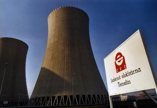 Zwei Kühltürme des Atomkraftwerks Temelín vor blauem Himmel, rechts ein Schild mit rotem CEZ-Logo und der Aufschrift »Jaderná elektrárna Temelín«.