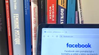 Bücherregal mit Büchern zu Feminismus und Frauenrechten, davor ein Bildschirm mit geöffneter Facebook-Webseite.