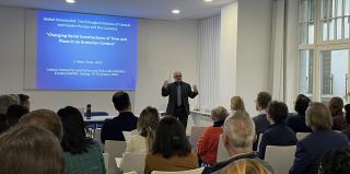 Vortragender steht vor einem Publikum in einem hellen Raum mit großen Fenstern und präsentiert eine Folie mit dem Titel 'Global Armenia/NS: The Entangled Histories of Central and Eastern Europe and the Caucasus'