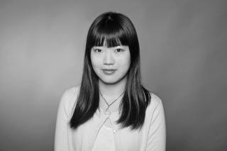 Schwarz-weiß Portrait, Frau mit langen, glatten Haaren vor einfarbigem Hintergrund.