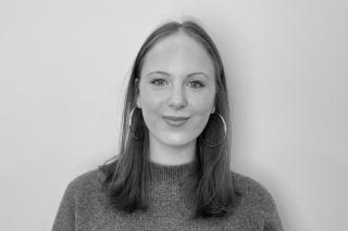 Portrait einer Person mit schulterlangen glatten Haaren und Kreolen in schwarz-weiß.