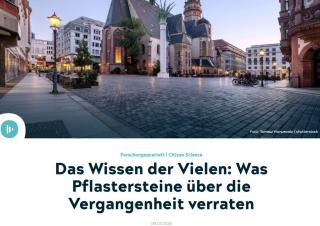 Weitwinkelaufnahme des Nikolaikirchhofs in Leipzig mit Kopfsteinpflaster, historischen Gebäuden und Fahrrädern am Abendlicht.