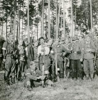 Gruppe bewaffneter und teilweise uniformierter Männer, im Wald stehend