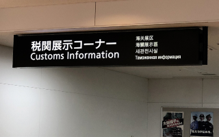 Schwarzes Schild mit weißer Schrift zeigt "Customs Information" in mehreren Sprachen an.
