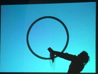 Schattenriss einer Person mit ausgebreitetem Arm vor einem blauen Hintergrund und einem schwarzen Kreis, Szene aus dem Theaterstück 'I Declare' (2011) von Alina Șerban.