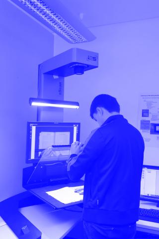 Eine Person steht an einem großen Buchscanner und positioniert gerade ein zu scannendes Buch.