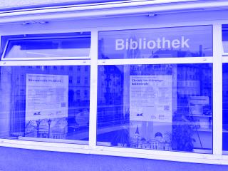 Fensterfront einer Bibliothek mit zwei großen Informationsplakaten zu Skowrodo-Museum und Christi-Verklärungs-Kathedrale.
