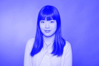 Schwarz-weiß Portrait, Frau mit langen, glatten Haaren vor einfarbigem Hintergrund.