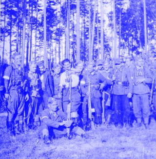 Gruppe bewaffneter und teilweise uniformierter Männer, im Wald stehend