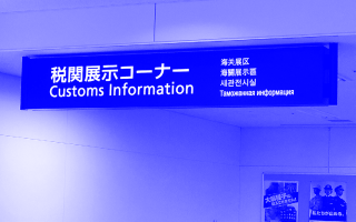 Schwarzes Schild mit weißer Schrift zeigt "Customs Information" in mehreren Sprachen an.