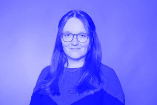 Portrait schwarz weiß: Frau mit langen Haaren, vor einfarbigem Hintergrund.