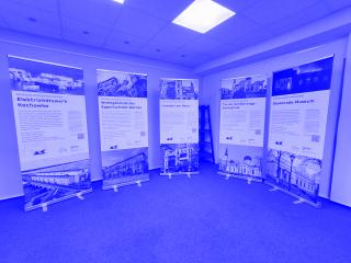 Fünf aufstellbare Ausstellungstafeln mit Texten und Fotos zu zerstörtem ukrainischem Kulturerbe in einem Raum mit blauem Teppichboden