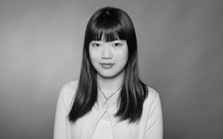 Schwarz-weiß Portrait, Frau mit langen, glatten Haaren vor einfarbigem Hintergrund.